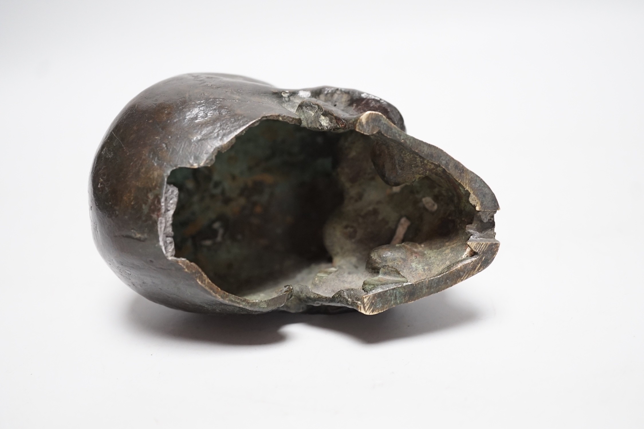 A bronze model of a skull, once part of a larger piece. 13cm deep